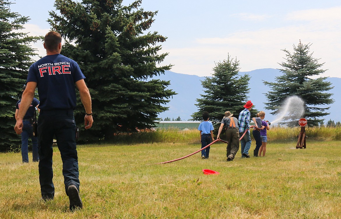 Photo by Mandi Bateman
Children learn to use a fire hose under the watchful eye of volunteer firefighters.