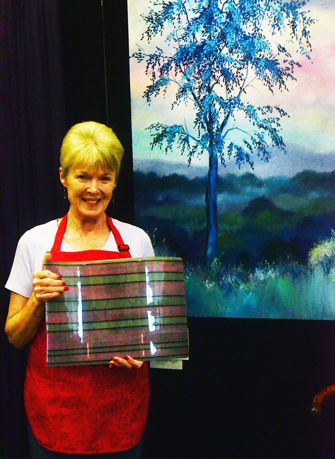 Karen M Thorson with two of her works showcased, &#145;Sweet Sixteen&#146; glass ware and &#145;Storm Across The Valley&#146; oil painting.
