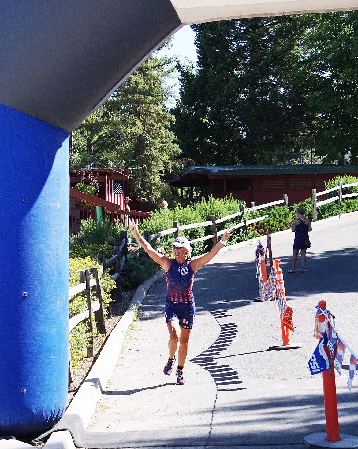 A triumphant racer crosses the finish line at City Beach during the Whitefish Lake Triathlon on Sunday.