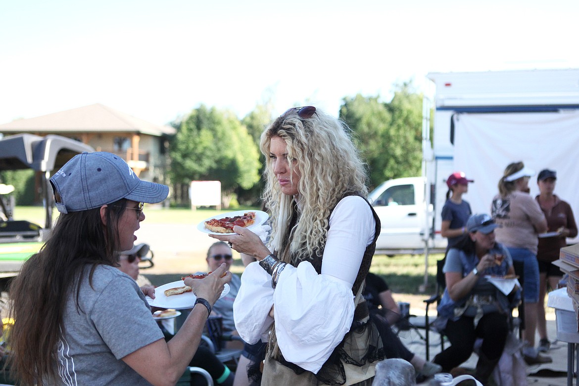 Heidi Martincic, of Paris, Montana, chats with Stephanie Revennaugh, of Livingston, over pizza at a benefit to raise awareness for rescue horses July 18. The social was hosted by members of  JMG Rescue Horses, who rescued 50 horses destined for slaughter last October, one of which competed at The Event and Rebecca Farm. (Mackenzie Reiss/Daily Inter Lake)