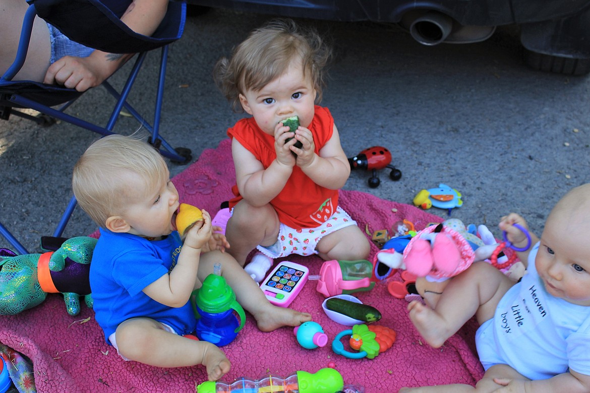 Gracie (right) and Ella (middle), who are both 1-year-old, and 6-month-old Ash (left), get into the spirit of the farmers market and munch on fresh lemons and cucumbers in Alberton.