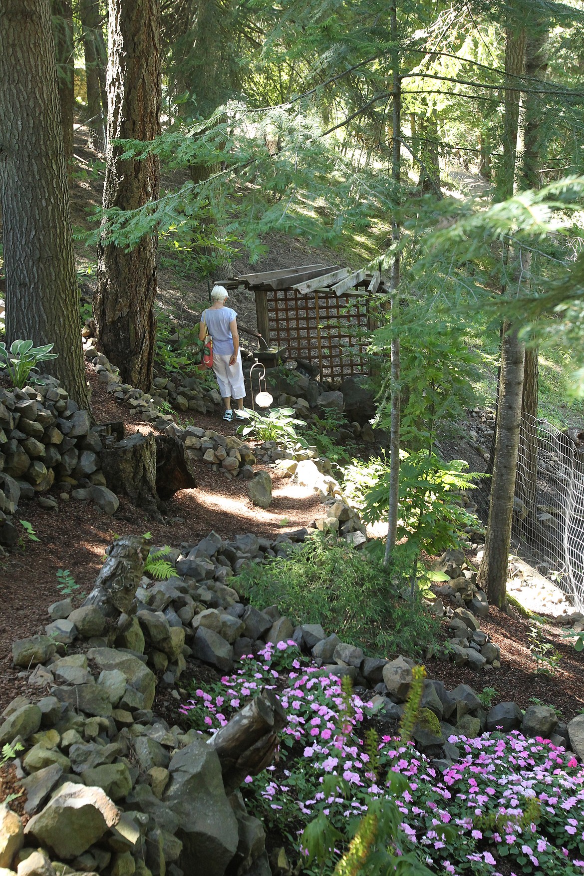 MITCHELL BONDS/Press
A visitor to the garden of Claudia Lowry and Bob Bloem explores one of the out-of-the-way and whimsical water features Sunday near the bottom of the steep garden during the 20th annual Garden Tour.