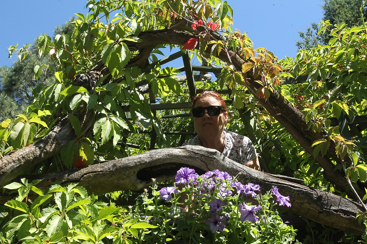 Carol Fidani pokes her head out one of the flowery bastion windows in the garden of Claudia Lowry and Bob Bloem during the 20th annual Garden Tour.

MITCHELL BONDS/Press