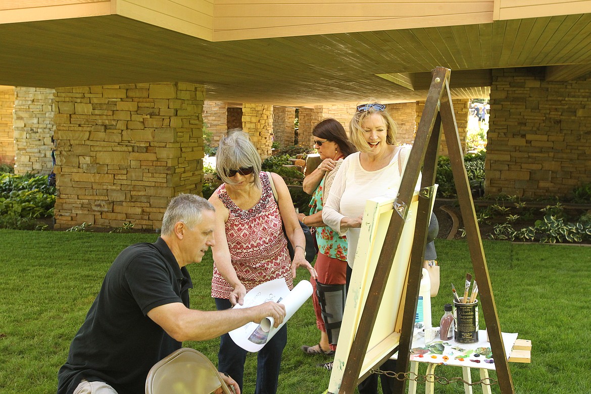 MITCHELL BONDS/Press
Landscape painter Leon Roulette, left, who painted the poster for the 20th annual Garden Tour, signs one of his posters for Connie Lipsker, center, and Sue Kellogg at the Hagadone Gardens on Sunday. &#147;It&#146;s unique in that it&#146;s actually a painting of a waterfall in (Hagadone&#146;s) garden,&#148; Kellogg said.