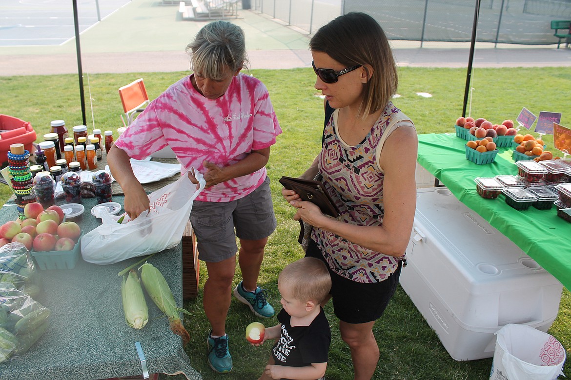 Charles H. Featherstone/Columbia Basin Herald
Chandra Govel and her son Malachai buy sweet corn from Tony Pritchett of White Trail Produce at the Quincy Farmers Market on Saturday.