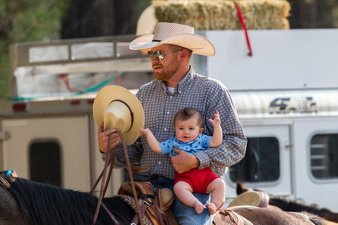 T.J. Heath of Joliet rides with his six-month old son Heston before the Kootenai River Stampede PRCA Rodeo in Libby Saturday, Aug. 5, 2017. Heath was a pickup man in the rodeo. (John Blodgett/The Western News)