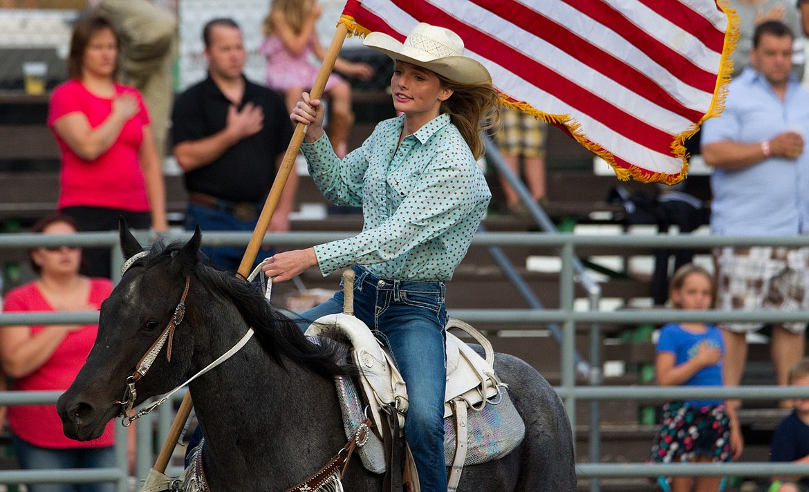 Callahan McMillan rides with the American flag at the start of the Kootenai River Stampede PRCA Rodeo in Libby Saturday, Aug. 5, 2017. (John Blodgett/The Western News)