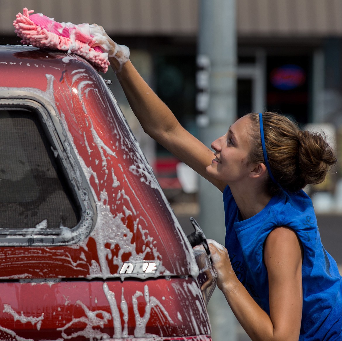 Aspen Swartzenberger participates in a fundraising carwash for the Libby High School volleyball team in front of Carquest Auto Parts in Libby Saturday, Aug. 5, 2017. (John Blodgett/The Western News)