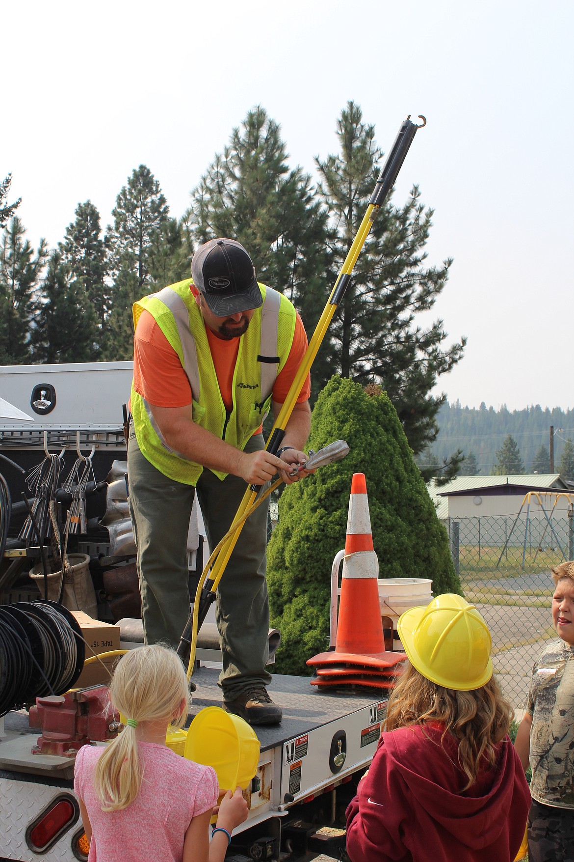 An Avista worker shows kids some of their toold of the trade. Avista also provided all of the kids with plastic hard hats to wear while they looked at all the vehicles.