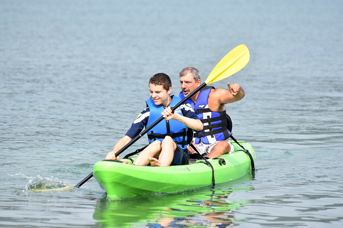 Kjell Sandler paddles in a kayak with direcion from volunteer Brian Luke Friday morning on Whitefish Lake during a DREAM Adaptive event at City Beach.