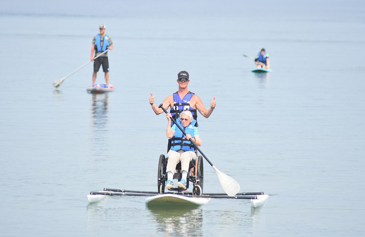 Volunteer Billy Harron gives a thumbs up as Sally Porcarelli paddles across Whitefish Lake Friday morning. (Heidi Desch/Whitefish Pilot)