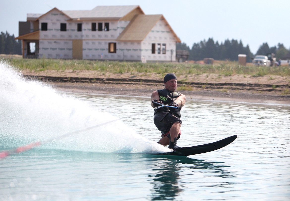 Water-ski competitor and Rosewater homeowner, Greg Alsbury water skis Wednesday at Rosewater water-ski community in Kalispell. Pictured behind Alsbury is his home, which he expects to be complete in September. (Mackenzie Reiss/Daily Inter Lake)