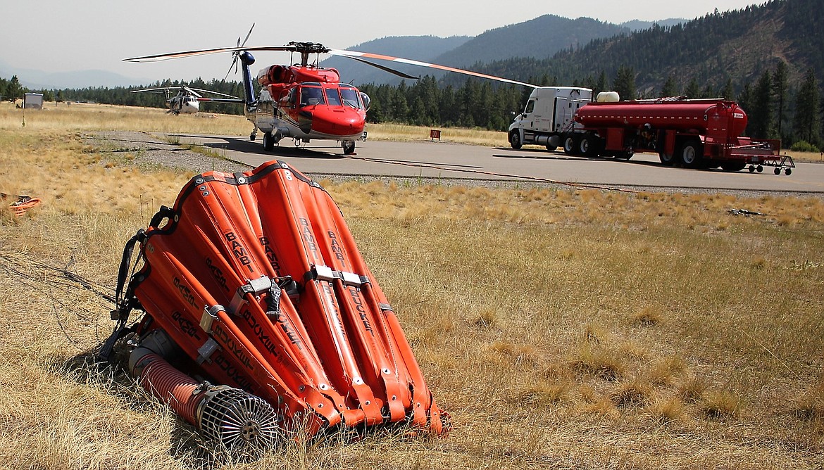 A Bambi Bucket with a pumps sits ready for use next to a Firehawk Helicopter and fuel tanker at the Mineral County Airport. It can carry up to 700 gallons of water. (Kathleen Woodford/Mineral Independent)