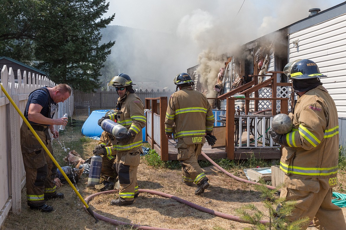 Left: Libby Volunteer firefighters &#151; from left, Scott Beagle, Brian Hobday, Eric Uithof and Paul Resch &#151; work the scene of a mobile home fire on Crossway Avenue in Libby Wednesday, Aug. 2. (John Blodgett/The Western News)