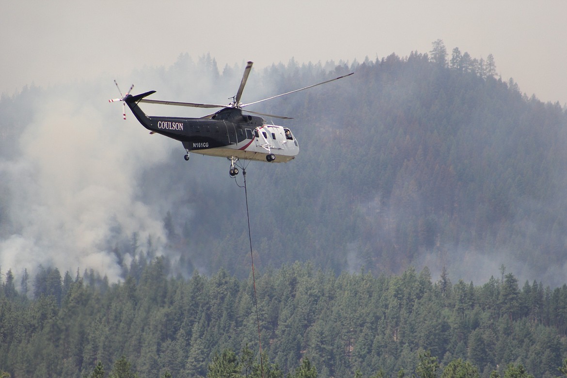 Helicopters drop gallons of water scoped from the Clark Fork River onto the Sunrise Fire burning east of Superior. (Kathleen Woodford/Mineral Independent)