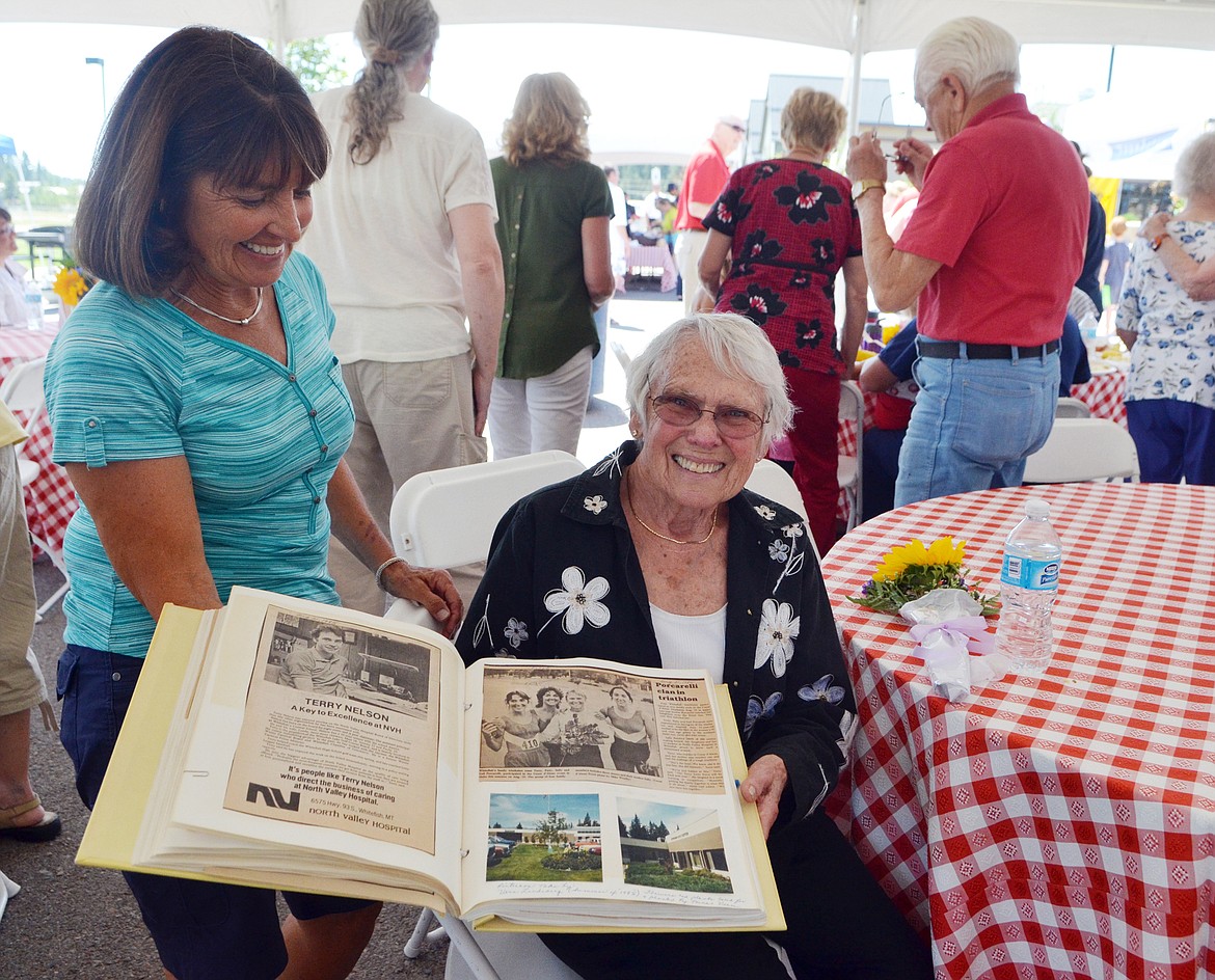 Sally Porcarelli, with the help of her daughter Patty Markuson, holds up a scrapbook from the North Valley Hospital Auxiliary that features an August 1985 Pilot article about her and her daughters. Porcarelli worked at the hospital for 28 years before retiring and was a member of the auxiliary. Several scrapbooks were on display last week during the hospital&#146;s picnic.