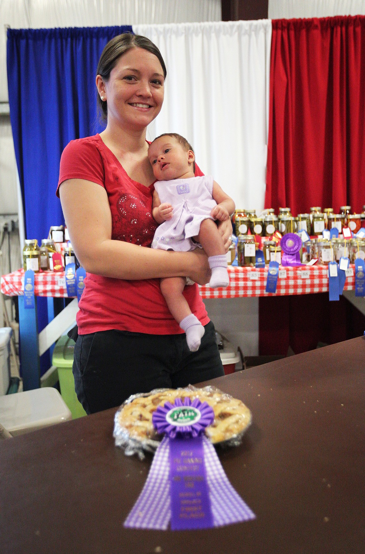 Melissa Friess of Kalispell holds her 7-week-old daughter, Amiah, shortly after winning first place in the Great American Pie Baking Contest at the Northwest Montana Fair. (Mackenzie Reiss/Daily Inter Lake)