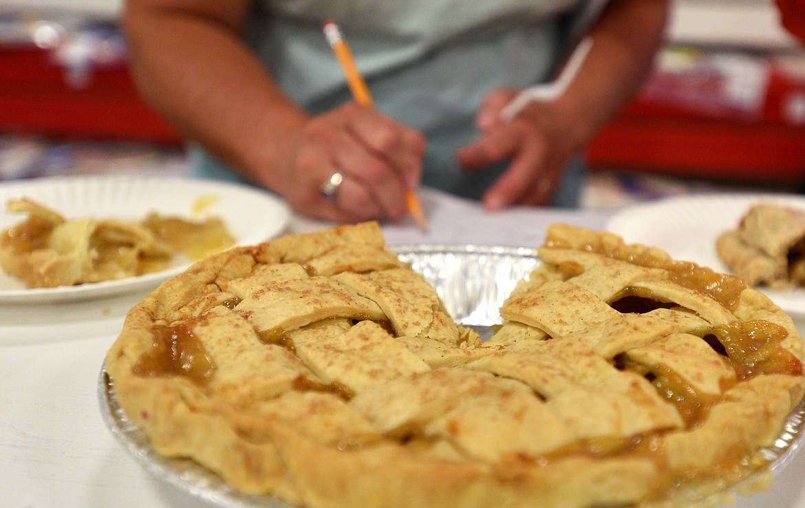 Karen Strong jots down notes after tasting a pie. (Aaric Bryan/Daily Inter Lake)