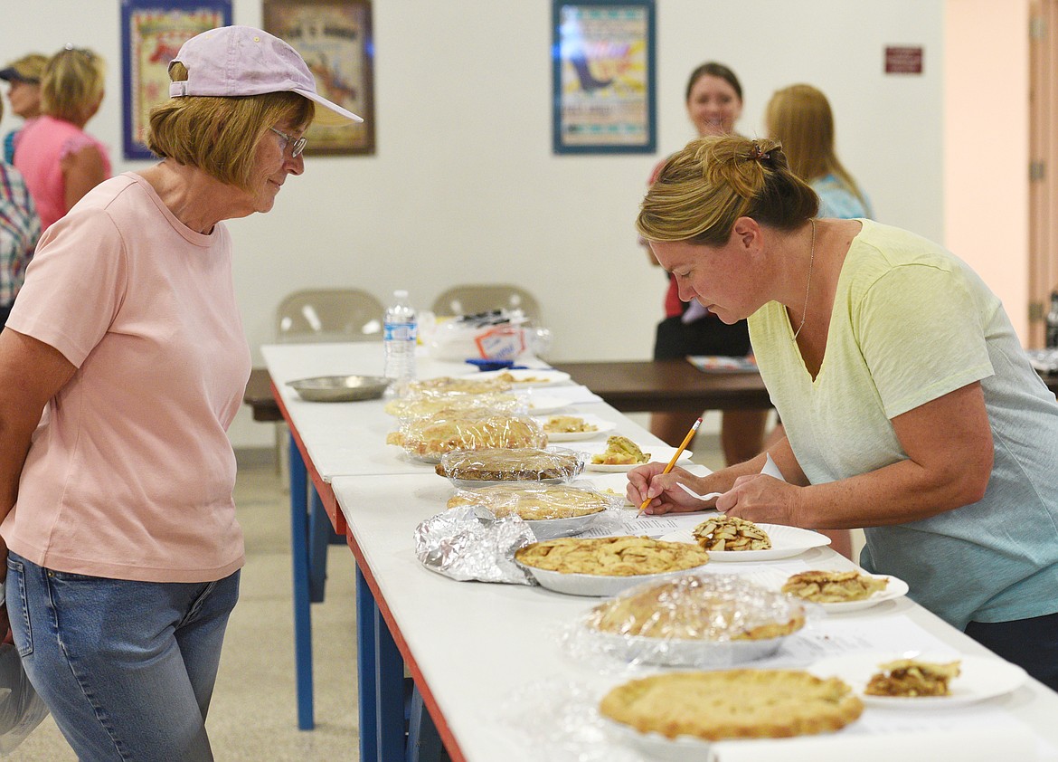 Carole Driscoll watches closely as Karen Strong judges her pie during the Northwest Montana Fair pie contest on Saturday. (Aaric Bryan/Daily Inter Lake)