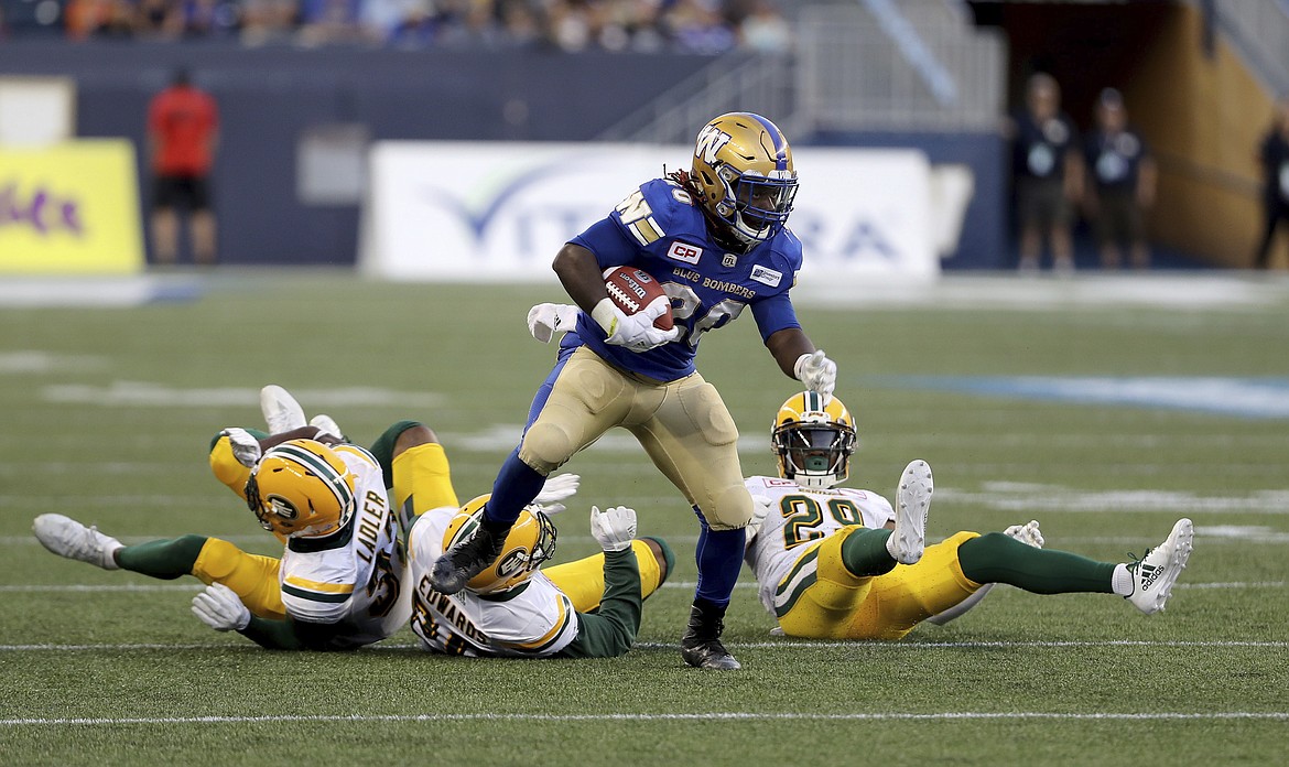 Three Edmonton Eskimos&#146; can&#146;t bring down Winnipeg Blue Bombers&#146; Timothy Flanders (20) during the first half of a Canadian Football League game Thursday in Winnipeg, Manitoba. (Trevor Hagan/The Canadian Press via AP)