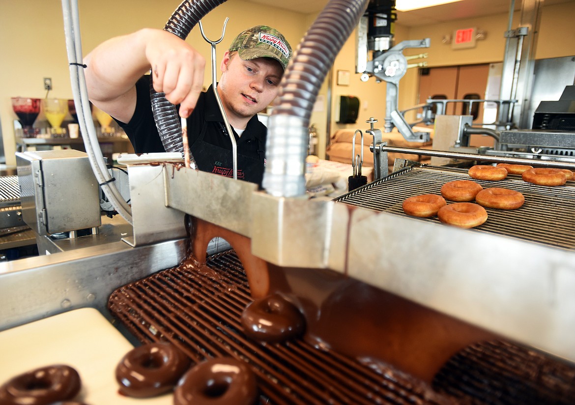 Tyler Martin, general manager of Krispy Kreme Doughnuts in Kalispell, does a test run demonstrating the new chocolate glaze which is a limited-time special offer coinciding with the solar eclipse. The doughnuts will be available beginning Friday, Aug. 18, at 6 p.m., through Monday, Aug. 21. (Brenda Ahearn photos/This Week in the Flathead)