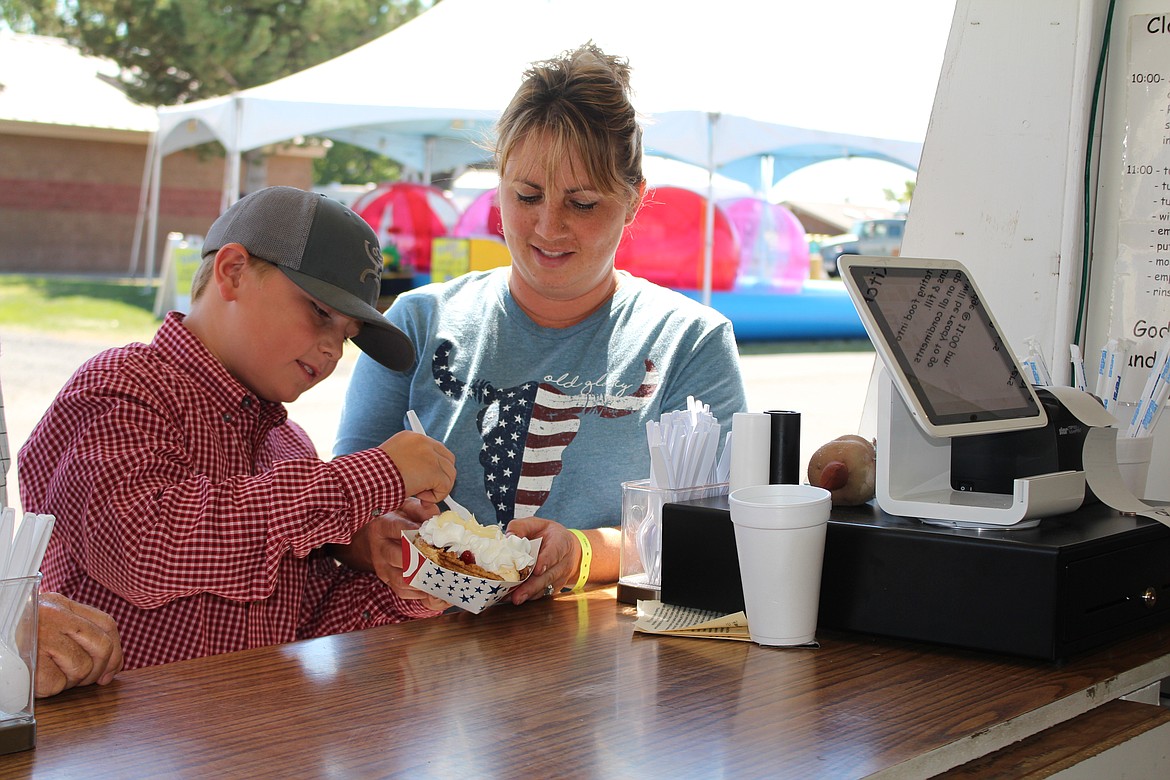 Cheryl Schweizer/Columbia Basin Herald
A customer digs into a strawberry waffle from the Youth Dynamics booth at the Grant County Fair.