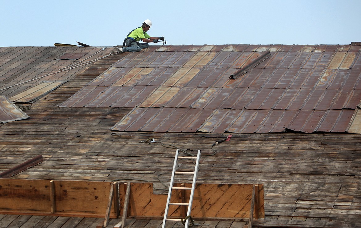 A Heritage Timber employee dismantles the tin roof of the Wright&#146;s Kalispell Lumber building Thursday, Aug. 10. (Mackenzie Reiss/Daily Inter Lake)