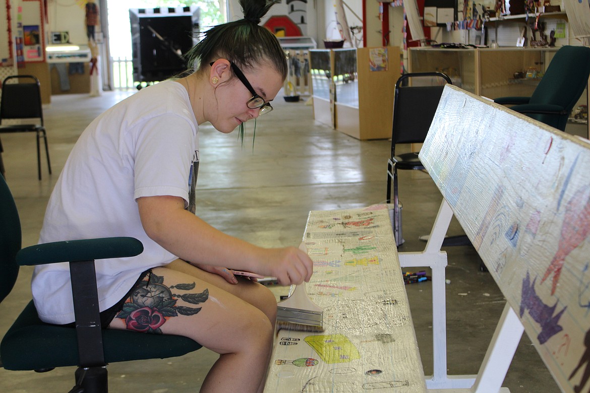 Cheryl Schweizer/Columbia Basin Herald
Jaymee Welch puts the finishing touches on a bench that will sit outside the arts and crafts building during the Grant County Fair. The fair opens today.