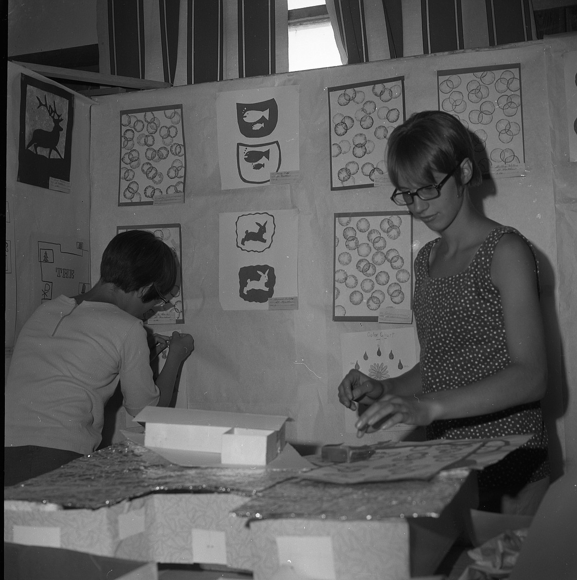 Linda Gardner, right, and Joan McGill, carefu;lly put up art work of students at St. Matthew’s in the elementary school building at the fairgrounds. School exhibits in 1967 displayed a variety of art work, including intricate “tissue” paintings and numerous drawings and crayon pictures.