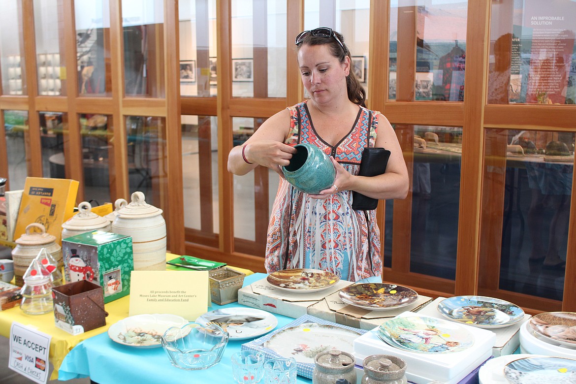 Cheryl Schweizer/Columbia Basin Herald
A shopper inspects some of the ceramics for sale at the Rusty Mammoth curated yard sale.