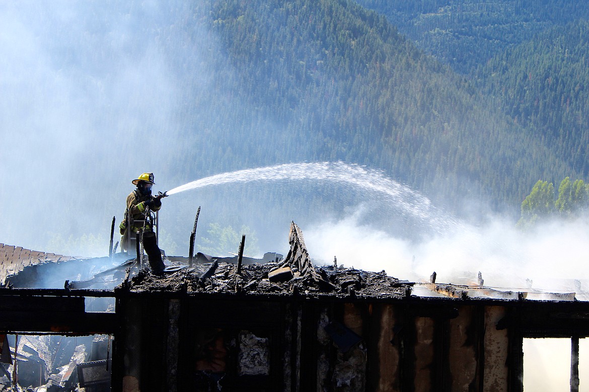 A firefighter conducts mop-up operations on the east end of the home.