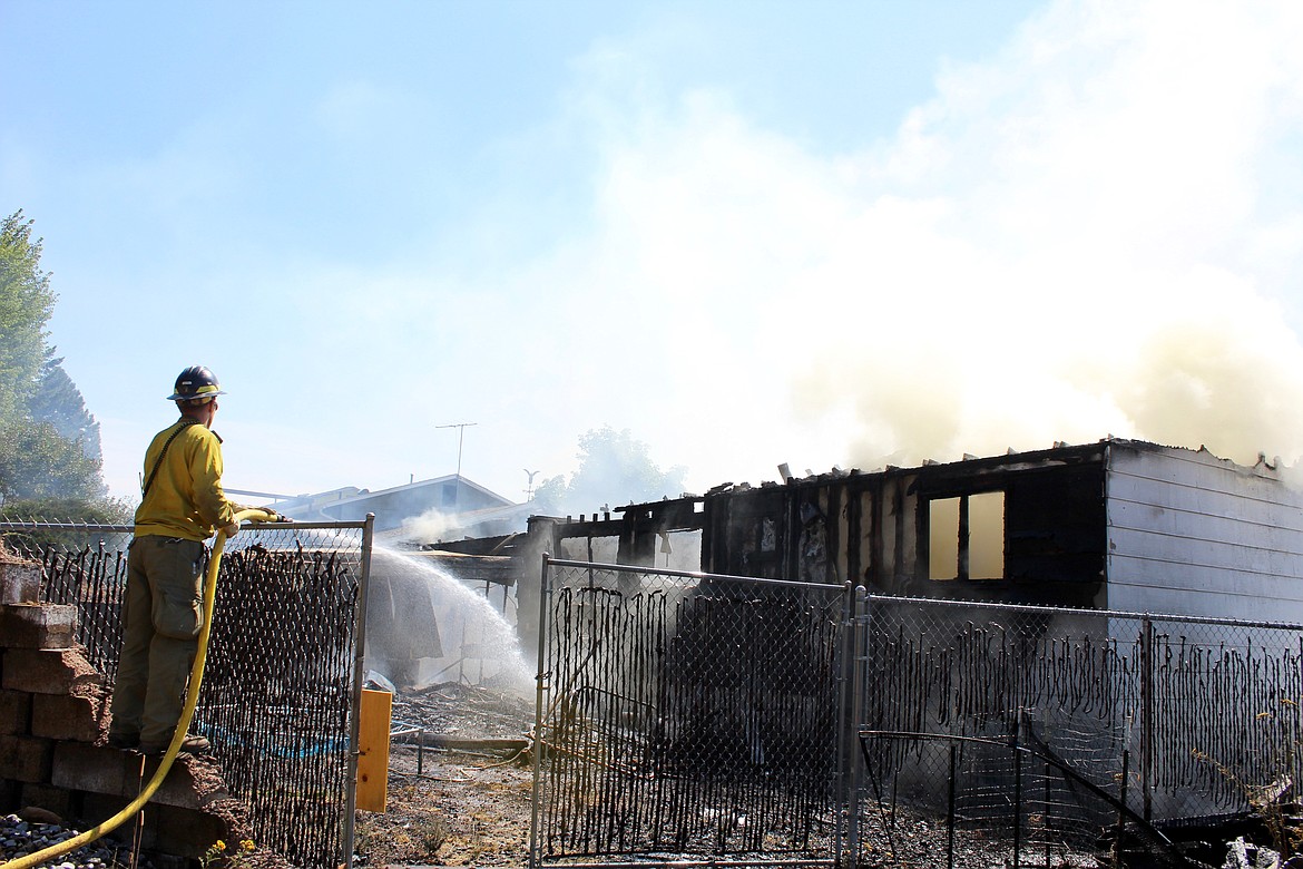 Chris Myers, IDL firefighter, hoses down the back yard and the North side of the building.