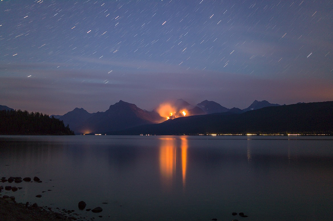 A starry night in Glacier Park as the Sprague Fire burns above Lake McDonald.