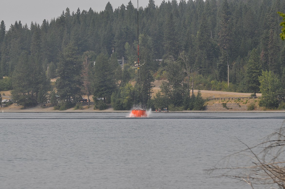 A bucket of water is dunked into Flathead Lake Saturday afternoon in an effort to contain the wildfire in the Blue Bay area on Highway 35.