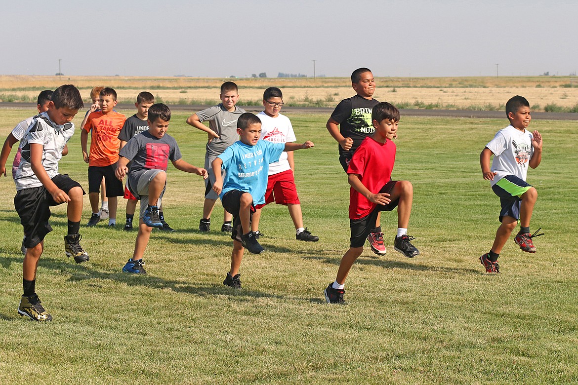 Bob Barrett photo - Would-be Huskie football players do warm up exercises during a youth football camp at Scootney Fields in Othello.