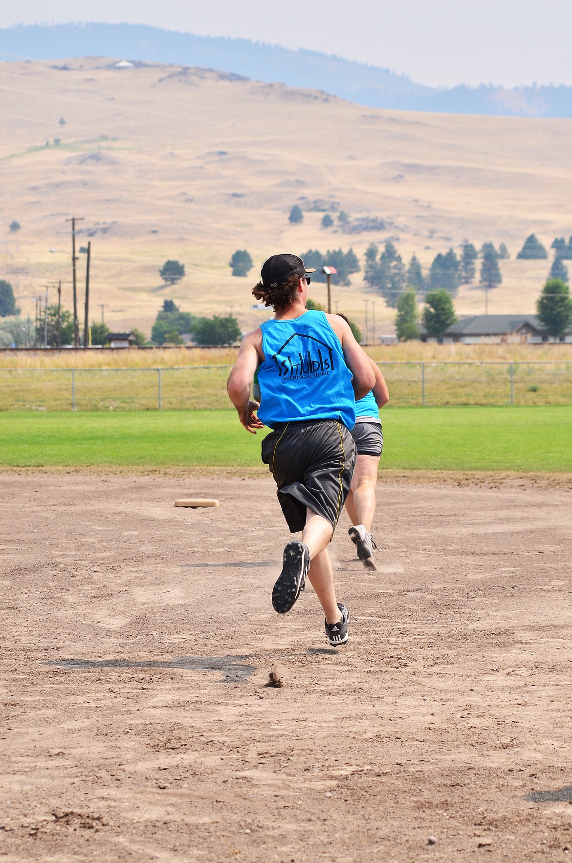 Kyle Brown running, Michele Bangen running infront. Both runners looking to get as far around the diamond as possible all thanks to Kyle's amazing hit into the outfield. Photo Credit Erin Jusseaume Clark Fork Valley Press