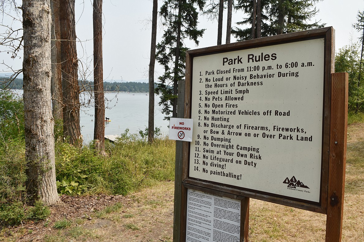 A sign at the Lake Park Addition list the rules for the Flathead County-owned park on Whitefish Lake. To the left, a group of cottonwood trees appear to be dead.  (Heidi Desch/Whitefish Pilot)