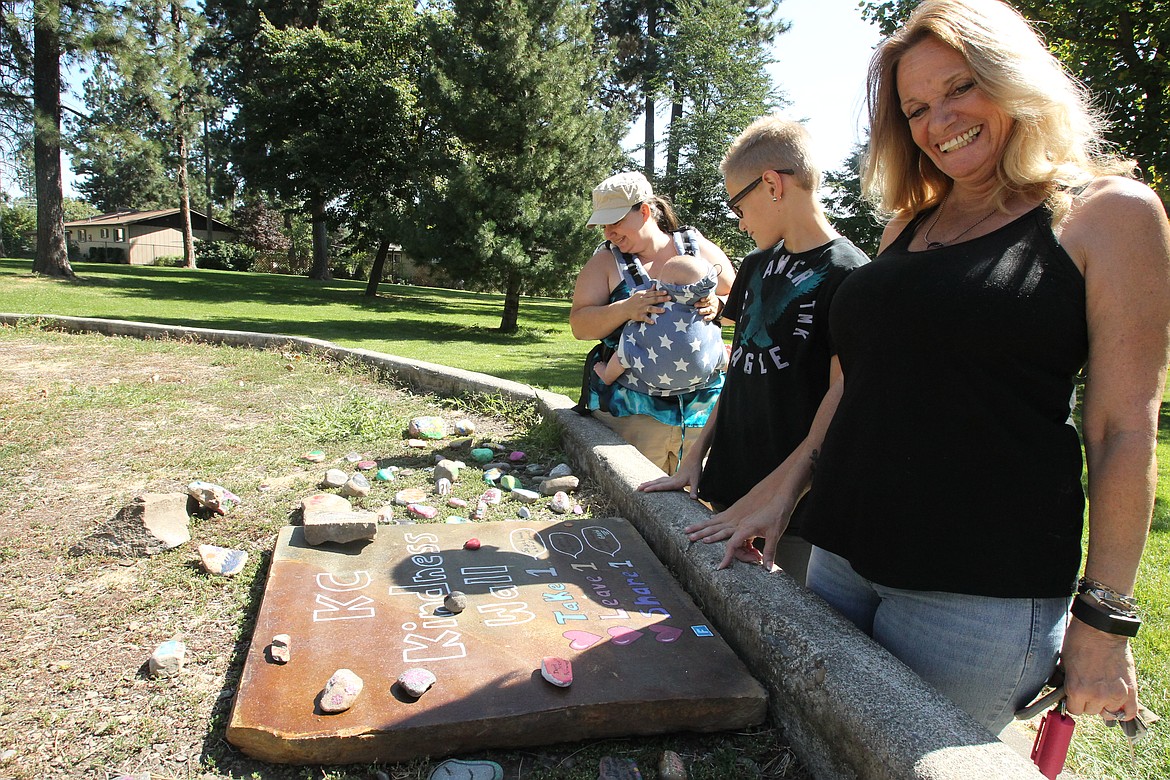 DEVIN HEILMAN/Press
Debby Carlson of Post Falls, right, son Aidan, 12, and Winn Koehler (with baby) scope out some of their favorite rocks Friday at the new Kootenai County Kindness Wall in White Pine Park in Post Falls. The wall was arranged by Koehler and other organizers of the new rock painting/hiding group, KC Rocks, for little kids and those with disabilities who cannot easily go out and hunt for cleverly hidden rocks.