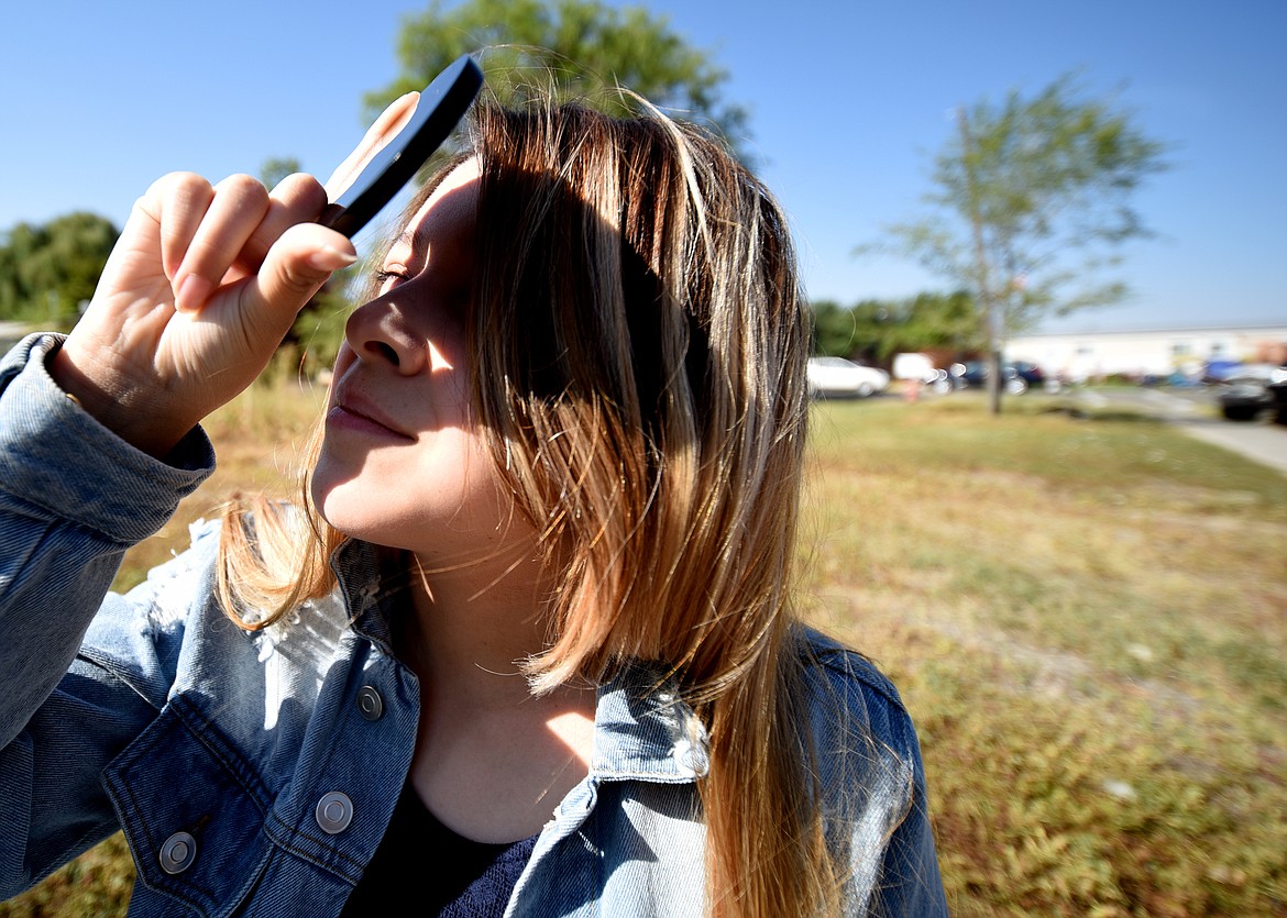 Melody Benchley, 13 of Hooper, Utah looks up at the eclipse through a disk of obsidian. Her family got the disks while traveling in South America. They were told that obsidian is what the ancient Aztecs used to view eclipses.(Brenda Ahearn/Daily Inter Lake)