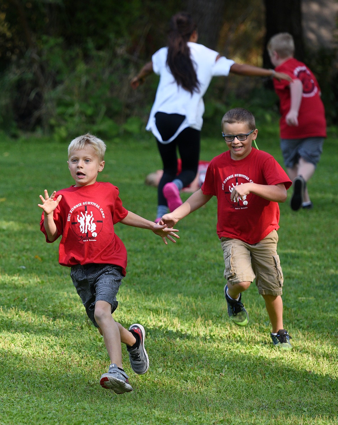 Tucker Lake, front, and Colton Howard run away from a Zombie during the Zombie Survival Camp at Woodland Park on Wednesday. The children at the 3-day camp learned survival techniques and skills like water purification, making smokeless fire, tracking, orienteering and building a bow and arrow. (Aaric Bryan/Daily Inter Lake)