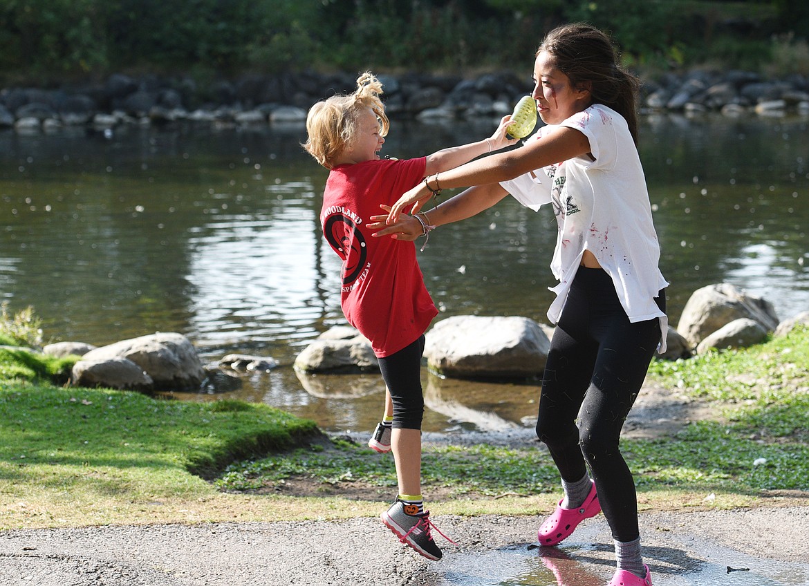 Piper McElwain, 7, throws a water grenade at zombie Selena Ikeda during Zombie Survival Camp at Woodland Park. Nearly 25 children participated in the three-day camp.