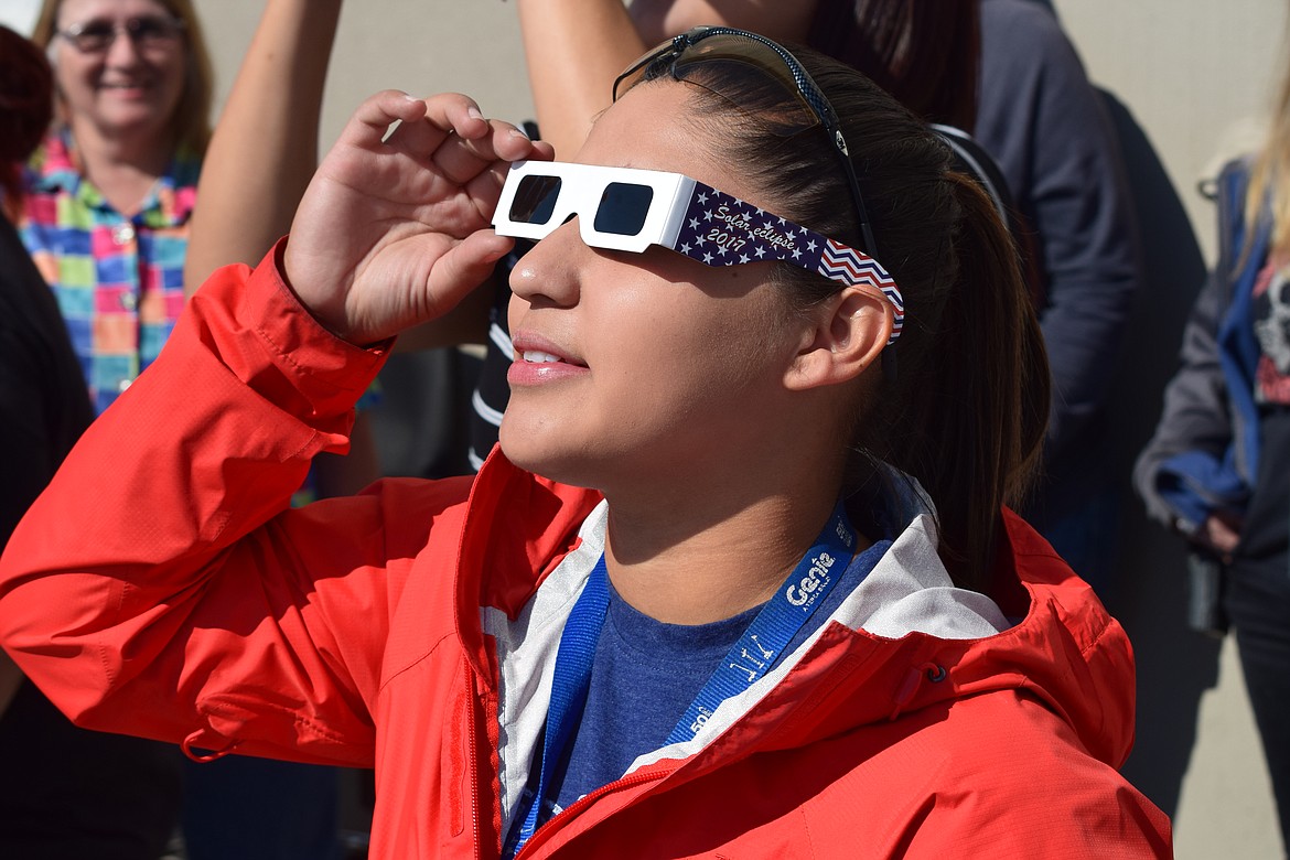 Charles H. Featherstone/Columbia Basin Herald -Genie employee Noami Villa looks on as the moon begins to obscure the sun during Monday morning's solar eclipse.