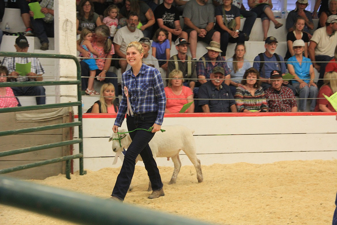 Photo By Tanna Larsen
Molly Flower beams to the crowd while leading her lamb during the auction.