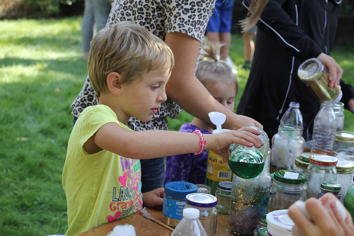 Willa Fredette, 5, creates a nebula in a jar using cottonballs and glitter during children activities in Alberton on Aug. 21. (Kathleen Woodford/Mineral Independent).