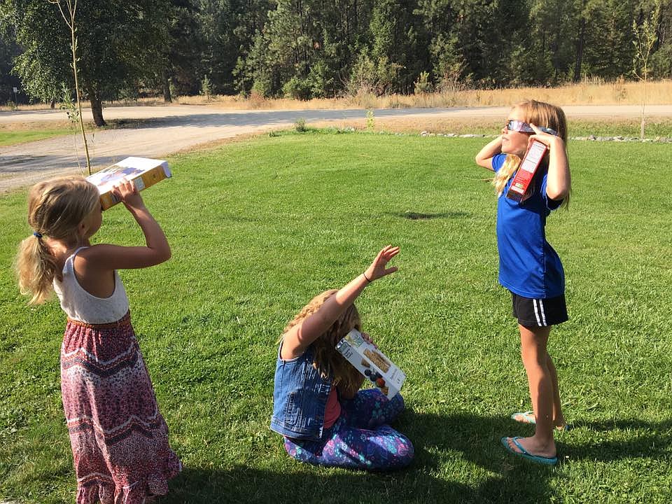 Using viewers made out of cereal boxes, Lily Jasper, 6, Lane DiGiando, 9, and Perri Jasper, 9, view the eclipse. (Photo courtesy of Darlene Kuprienko Jasper).