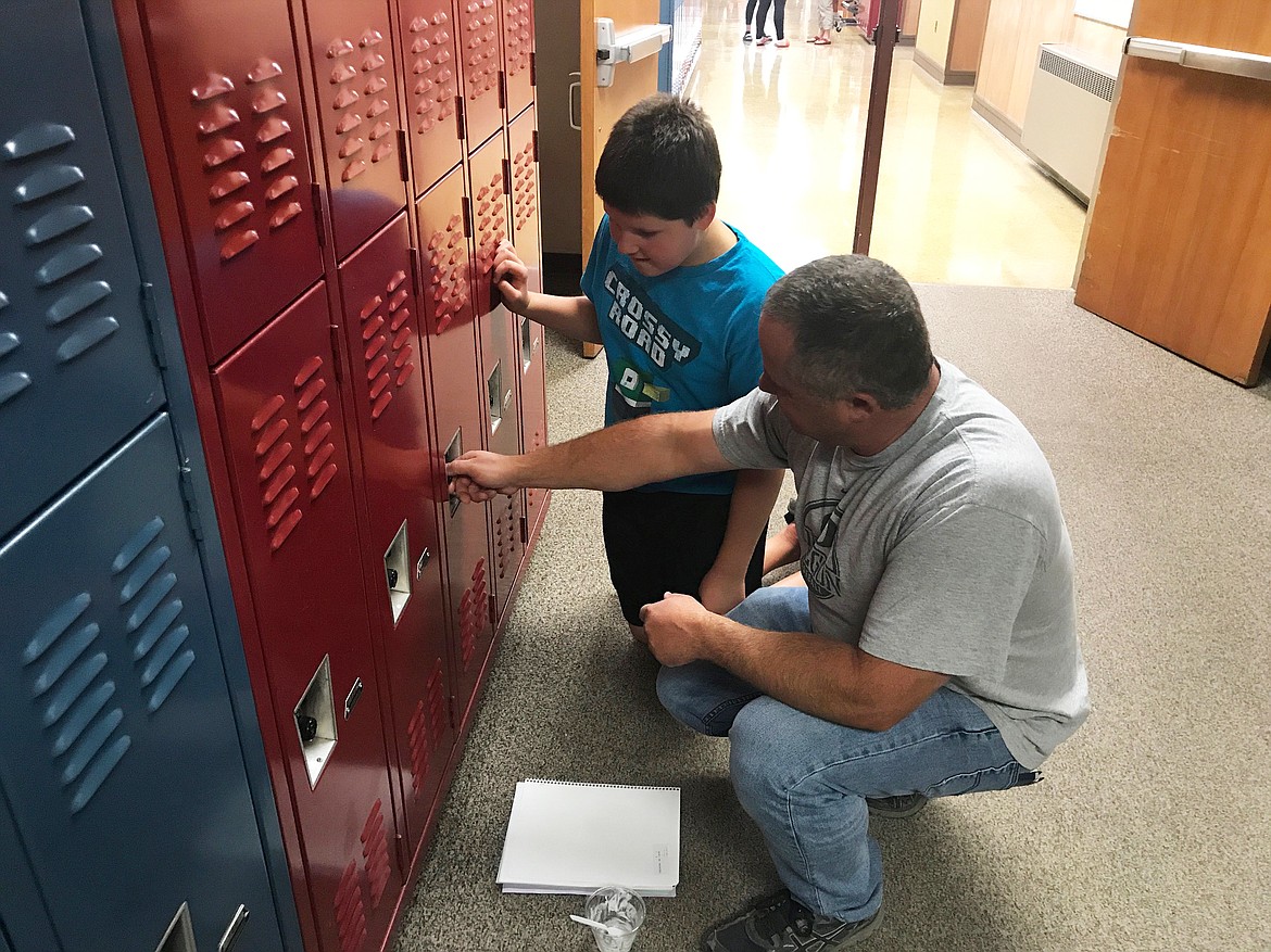 Chancy Jeschke helps his son Cody, 12, practice the combination to his locker at Evergreen Junior High School during Student Experience Day. The day is an opportunity for families to complete registration paperwork and students to meet teachers and organize supplies.