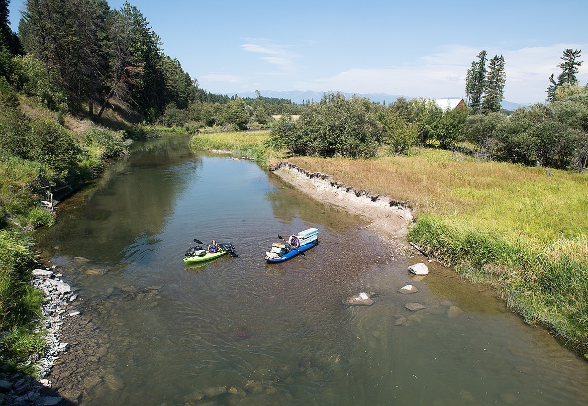 Loaded with junk, Sarah Downs and her mother, Laura Katzman, float the Whitefish River.