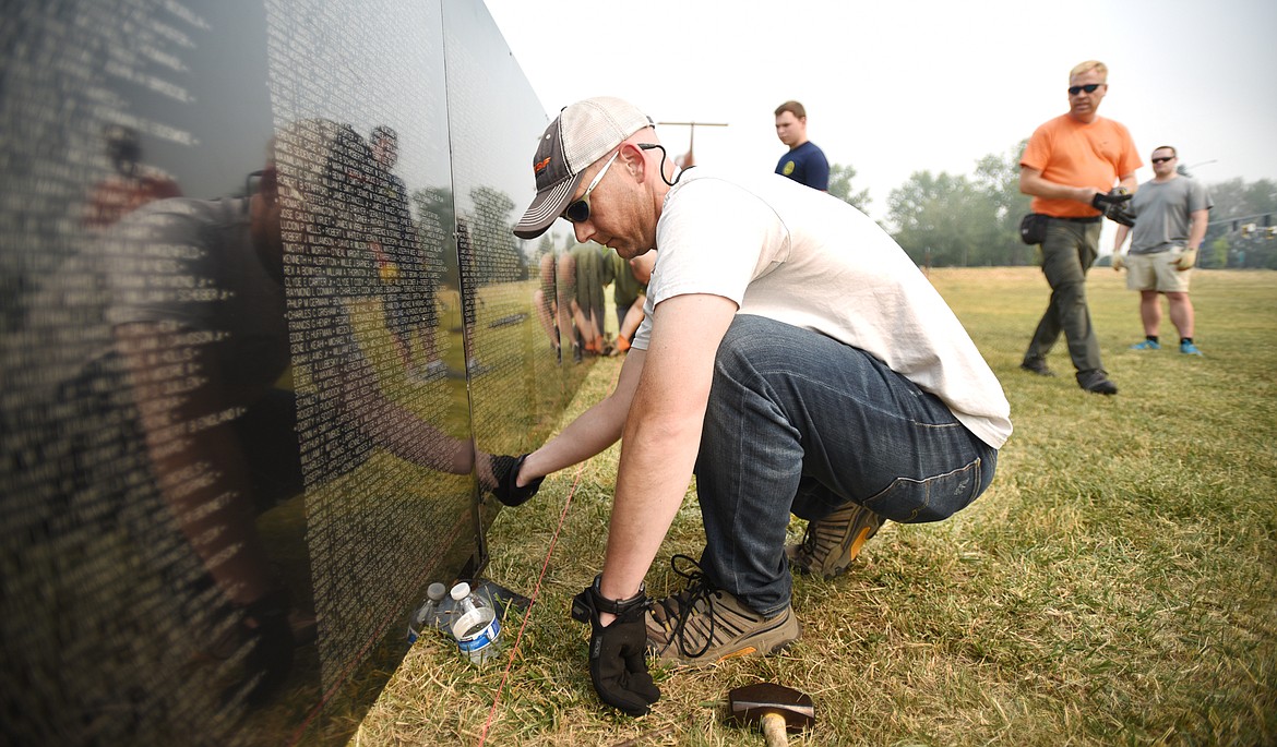 Officer Andy Haag of the Kalispell Police Department carefully lines up the panels of the wall before fixing them in place on Wednesday afternoon, September 6, in Kalispell. The Wall that Heals, a mobile replica of the Vietnam Veterans Memorial in Washington, D.C. arrived in Kalispell a little after 11 a.m. The Wall, which is made up of 100 aluminum panels, was put up by volunteers, including 15 members of the Kalispell Police Department, starting around 1 p.m. The Wall that Heals will have an opening ceremony today at 10 a.m. in the large field adjacent to Rosauers. After which it will be open 24 hours per day for free to visitors. There will be ceremonies all four days the Wall is in Kalispell including two on Sunday, September 10, the first will be the daily opening ceremony at 10 and a closing ceremony at 4 p.m.&#160;Mike Shepard of Columbia Falls Freedom Post #72 said that on the Vietnam Veterans Memorial there are 11 names of service members who died who were from the Flathead Valley. There are a total of 270 Montanans listed on the Wall and 107 Canadians. Shepard said that he and some of the Columbia Falls veterans went to Kimberly, British Columbia for a veterans memorial dedication. Some of those Canadians they went to visit are returning the honor and will be at the opening ceremony today.(Brenda Ahearn/Daily Inter Lake)