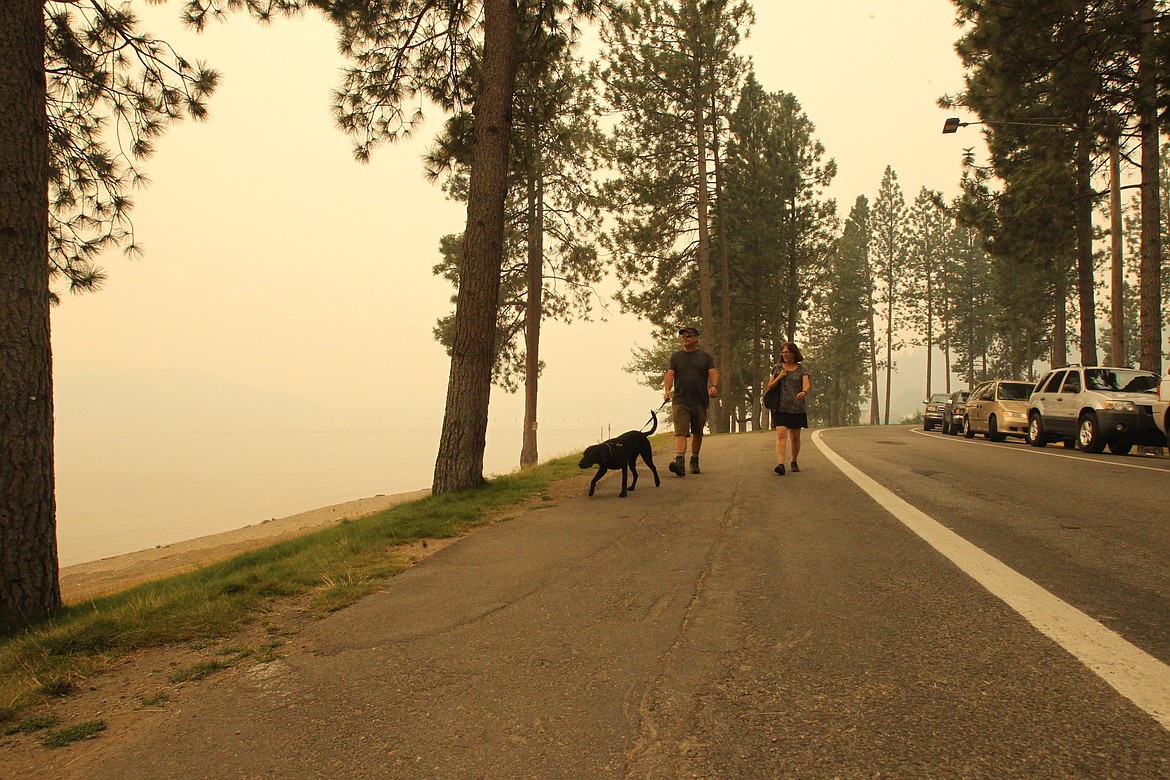 DEVIN HEILMAN/Press
Steve and Gaylyn Meyers of Los Alamos, N.M., walk their black Lab Joey on the Dike Road by North Idaho College as smoke blankets Lake Coeur d'Alene and reduces visiblity on Tuesday.