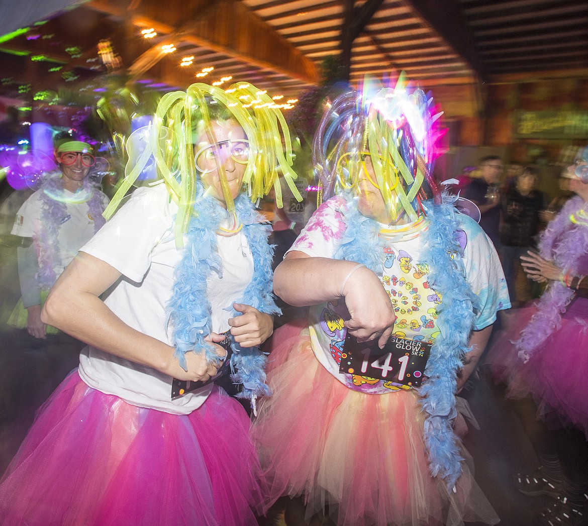 Jill Lewis and Dayna Lehrman dance at the start of the Glacier glow Run in Columbia Falls Friday night.